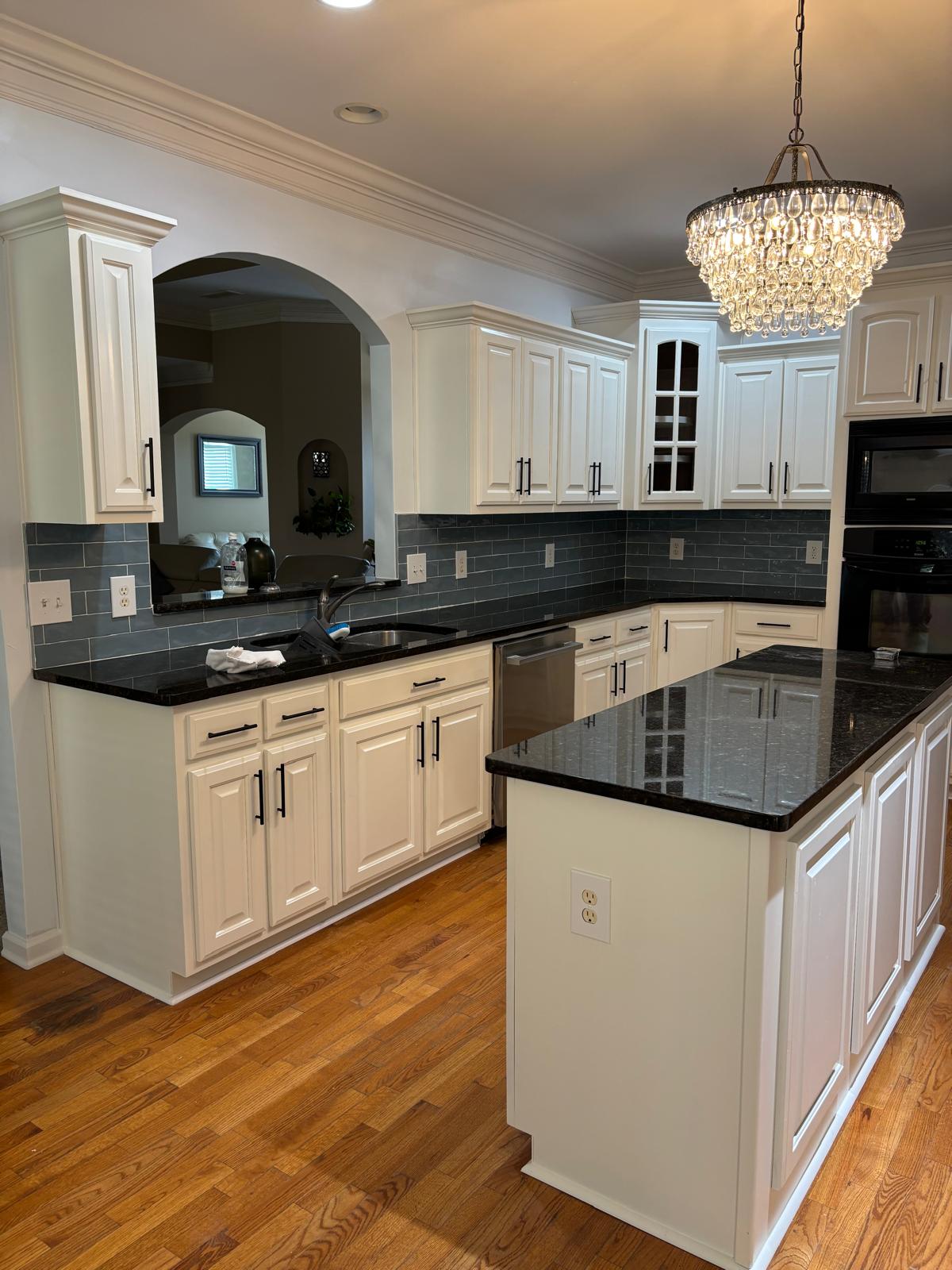 Refinished white kitchen with black granite counters and hardwood floors after an interior remodel in Snellville, GA